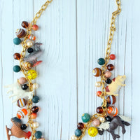 Long statement necklace with a mix of dark colored beads and farm animal charms. Charm necklace with farm animal charms.