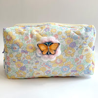 Pastel floral cotton quilted makeup bag embellished with an orange butterfly with rhinestones brooch over a crochet flower. Cute makeup bags with zipper. Bridesmaid gifts for proposal.