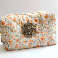 Orange flowers on a cream cotton fabric quilted zipper pouch. Quilted makeup bag embellished with a large star shaped rhinestone brooch. Cute makeup bags with zipper. Gifts for mom.