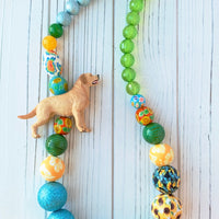 Long beaded Labrador Retriever necklace. Beaded necklace with toy yellow Labrador Retriever strung with blue beads, green beads, yellow beads and sunflower beads.