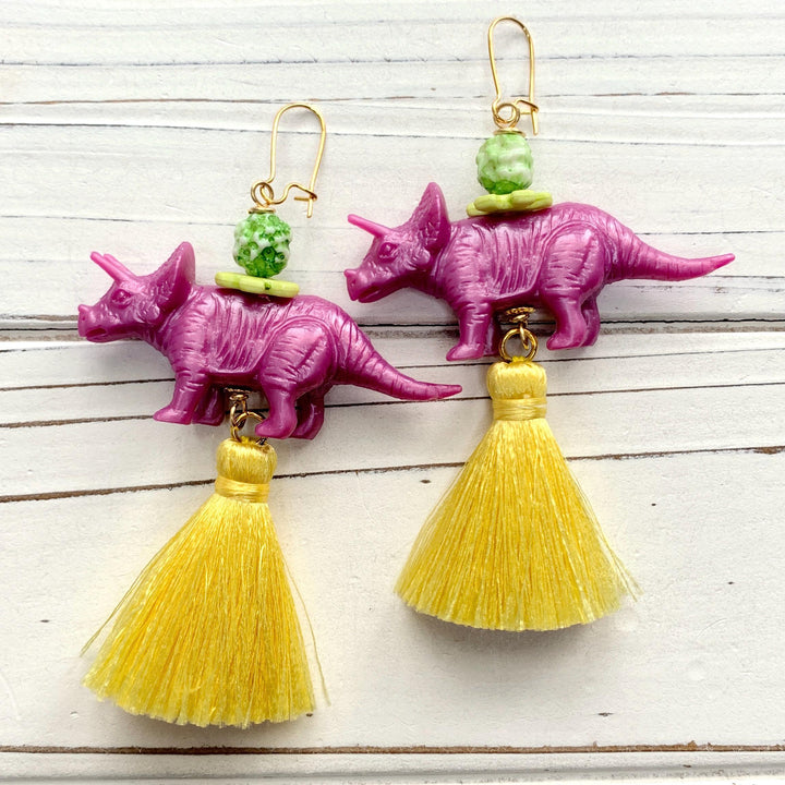 Purple triceratops earrings with yellow tassels. Miniature dinosaur earrings for women. 