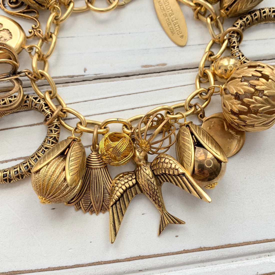 Chunky gold charm bracelet for women. Gold bird charm and other interesting gold tone charms on a brass plated chain.