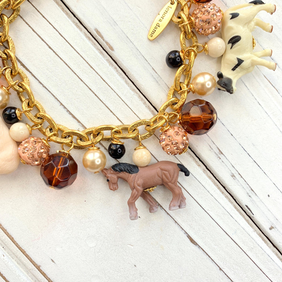 Miniature horse charm on a gold chain charm bracelet.