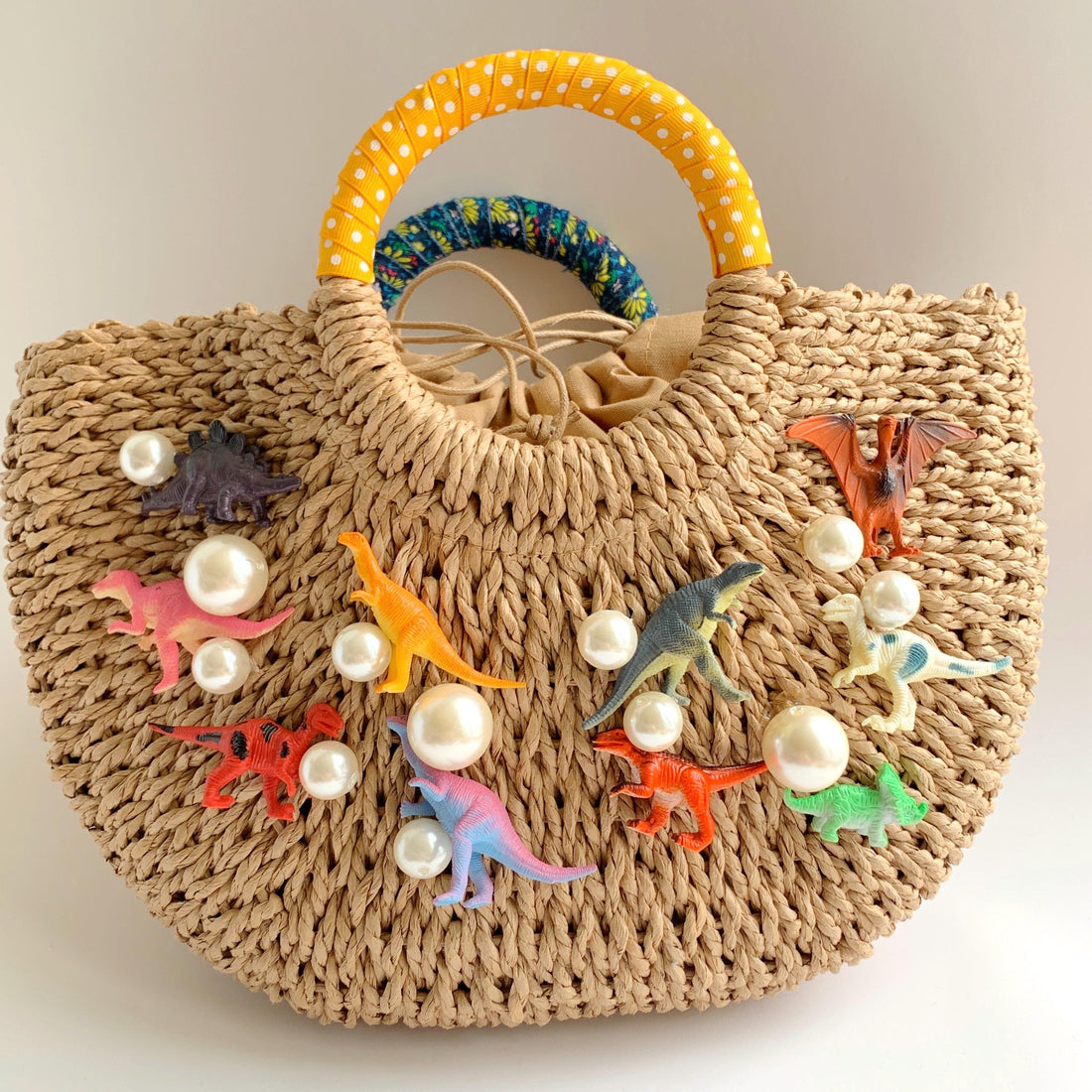 Medium  straw bag for summer embellished with colorful toy dinosaurs and pearls. Top handle woven bag.