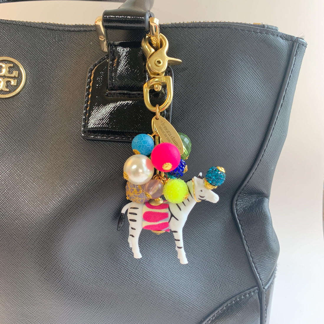 Colorful cute bag charm on a black handbag. Lenora Dame bag charms.