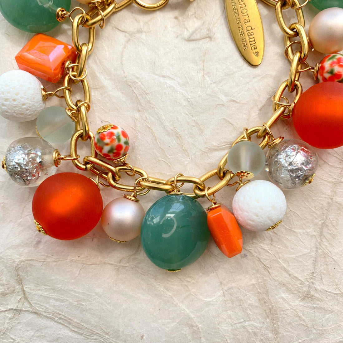 Lime green beads, orange beads, white beads, silver beads wire wrapped on a gold chain.