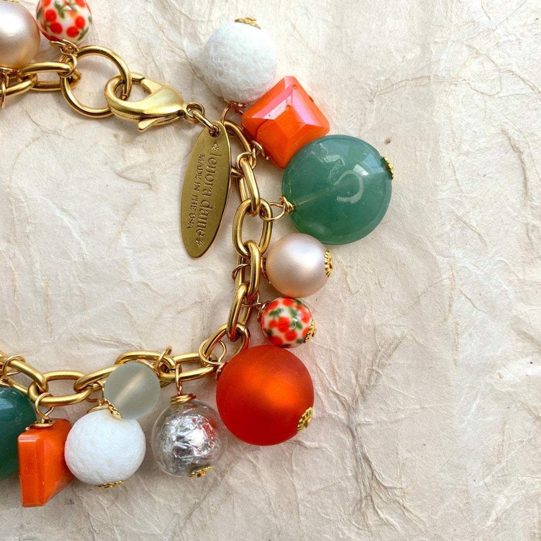 Lime green beads, orange beads, white beads, silver beads wire wrapped on a gold chain.