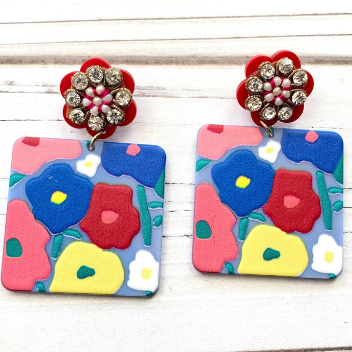 Floral drop earrings with square piece with flower design hanging from red rhinestone flower post earrings. Lenora Dame jewelry.