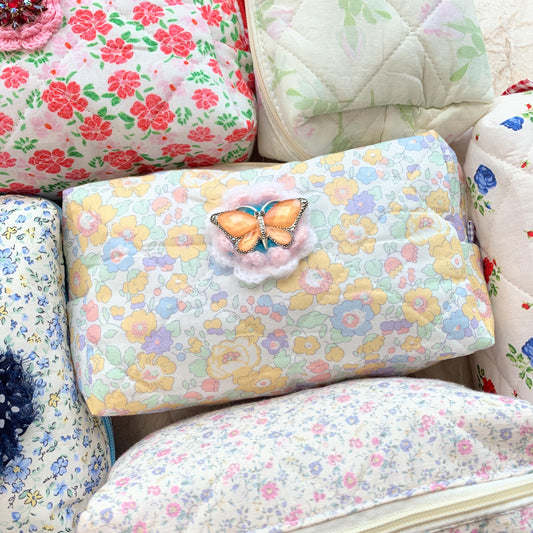 Pastel floral cotton quilted makeup bag embellished with an orange butterfly with rhinestones brooch over a crochet flower. Cute makeup bags with zipper. Bridesmaid gifts for proposal.