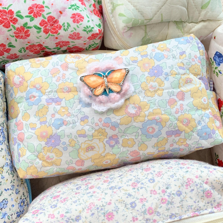 Pastel floral cotton quilted makeup bag embellished with an orange butterfly with rhinestones brooch over a crochet flower. Cute makeup bags with zipper. Bridesmaid gifts for proposal.
