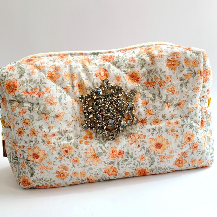 Orange flowers on a cream cotton fabric quilted zipper pouch. Quilted makeup bag embellished with a large star shaped rhinestone brooch. Cute makeup bags with zipper. Gifts for mom.