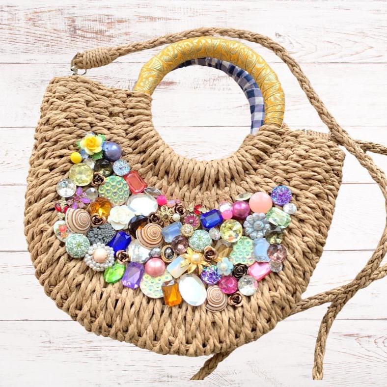 Small half-moon straw bag embellished with a tight collage of flowers, seashells, vintage buttons, large rectangular gemstones, vintage brooches and metal flowers. Rhinestone embellished cute straw bag for summer with top handle and removable shoulder strap or crossbody strap.