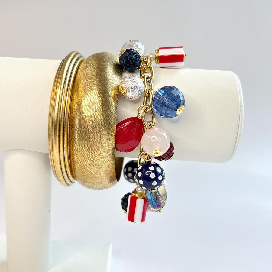  Red, white and blue charm bracelet with polka dot beads, striped beads, red rhinestone beads, and blue rhinestone beads on a gold link chain. Patriotic jewelry for women. Lenora Dame jewelry. 
