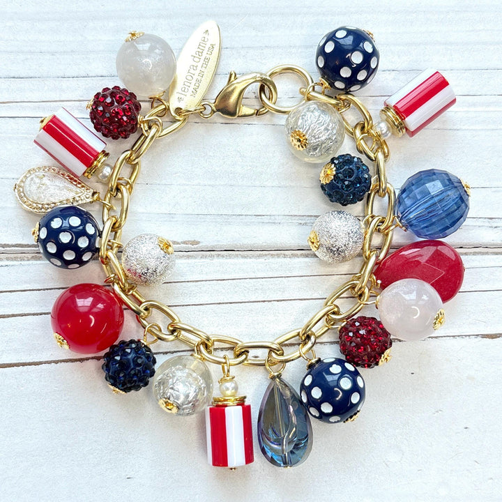  Red, white and blue charm bracelet with polka dot beads, striped beads, red rhinestone beads, and blue rhinestone beads on a gold link chain. Patriotic jewelry for women. Lenora Dame jewelry. 