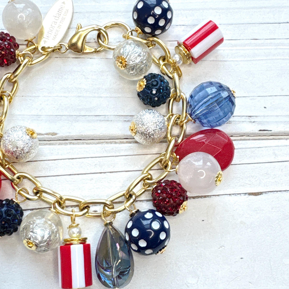  Red, white and blue charm bracelet with polka dot beads, striped beads, red rhinestone beads, and blue rhinestone beads on a gold link chain. Patriotic jewelry for women. Lenora Dame jewelry. 