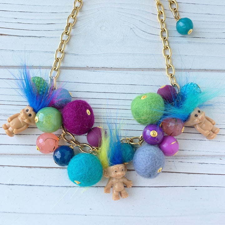 Troll dolls necklace with miniature trolls dolls with crazy hair and a mix of felt balls and beads on a gold chain.