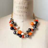 Gold plated cable chain Halloween necklace with orange pumpkins and carved jack-o'-lantern charms, miniature skulls and black and white beads.