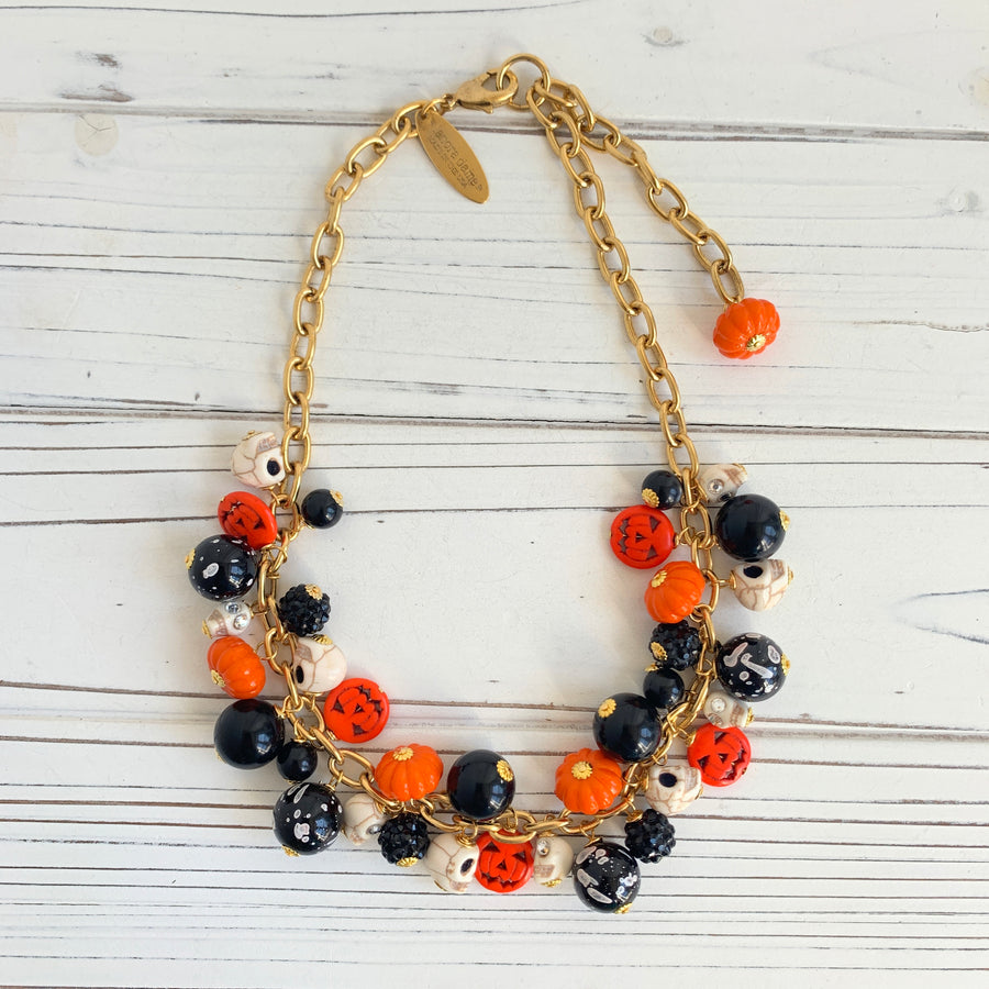 Gold plated cable chain Halloween necklace with orange pumpkins and carved jack-o'-lantern charms, miniature skulls and black and white beads.