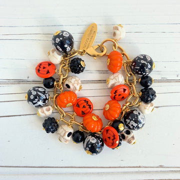 Gold plated cable chain Halloween bracelet with orange pumpkins and carved jack-o'-lantern charms, miniature skulls and black and white beads.